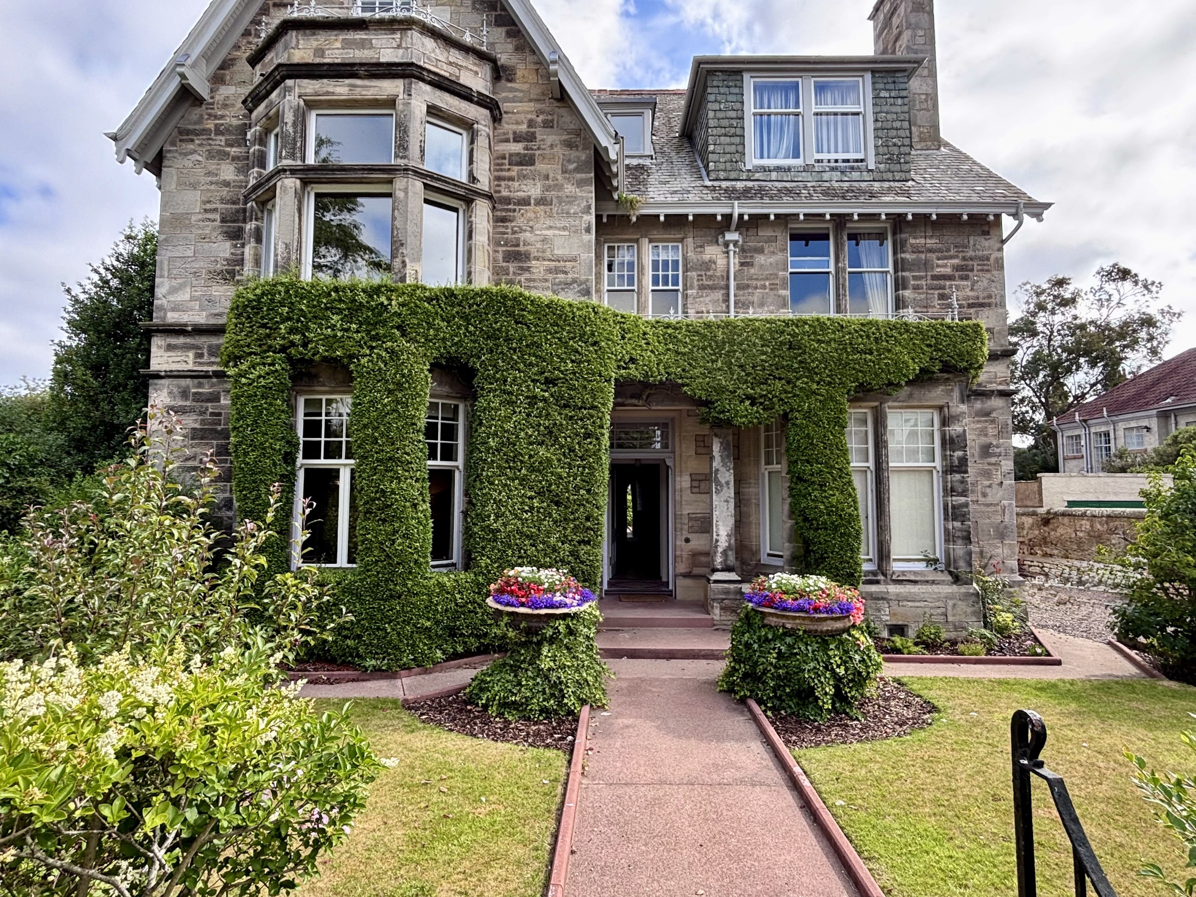 Firethorn House stone facade with ivy, flowers and the entrance path