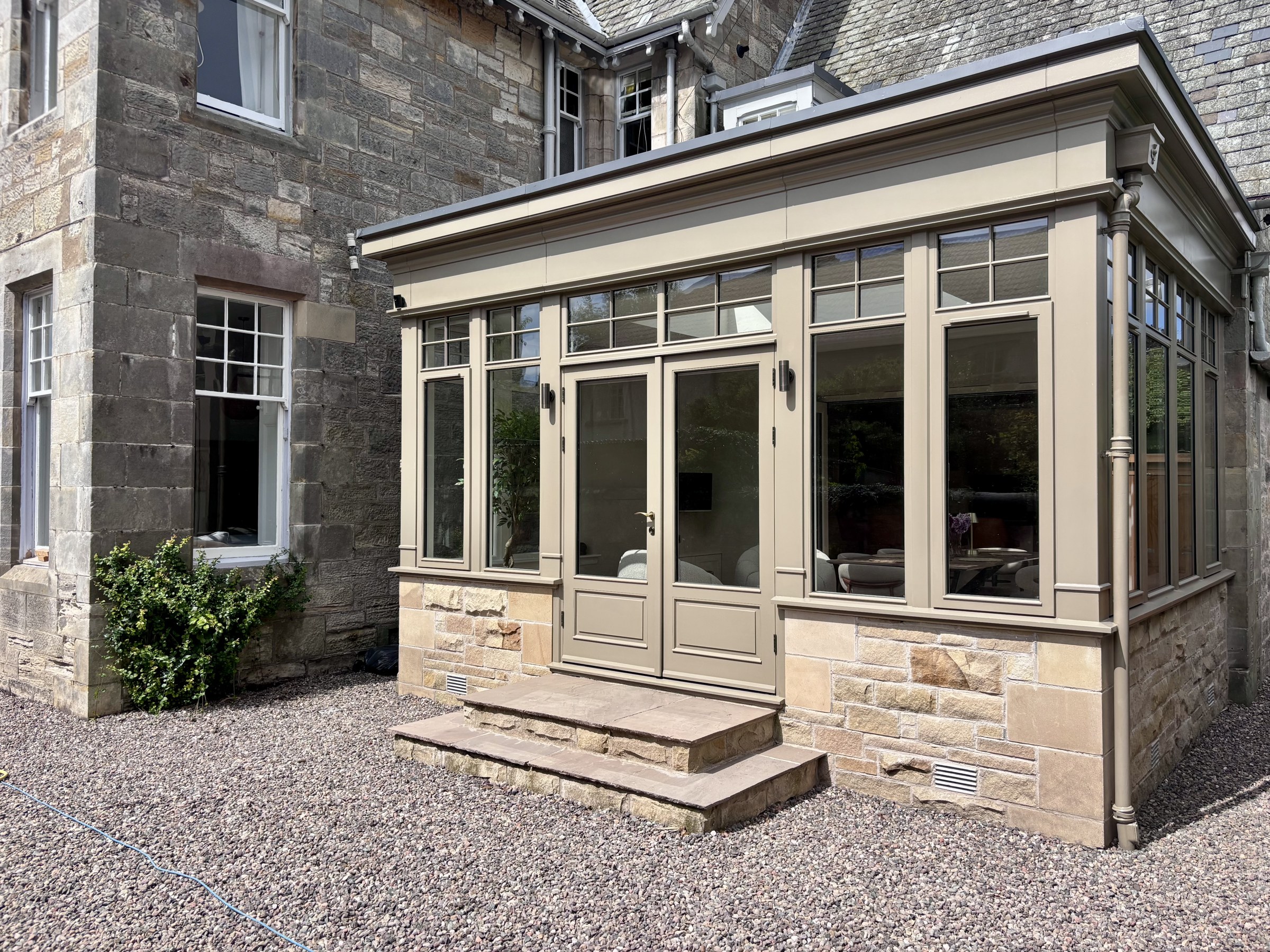 Stone exterior and glazed conservatory opening onto the patio