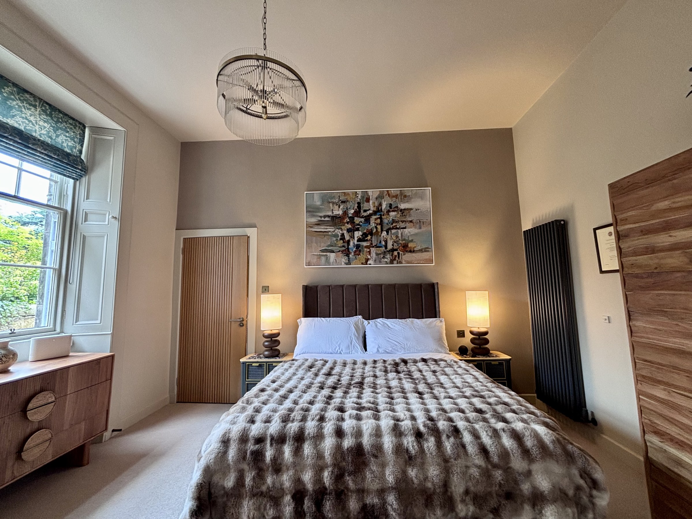 Bedroom with a patterned throw, wardrobe and framed artwork