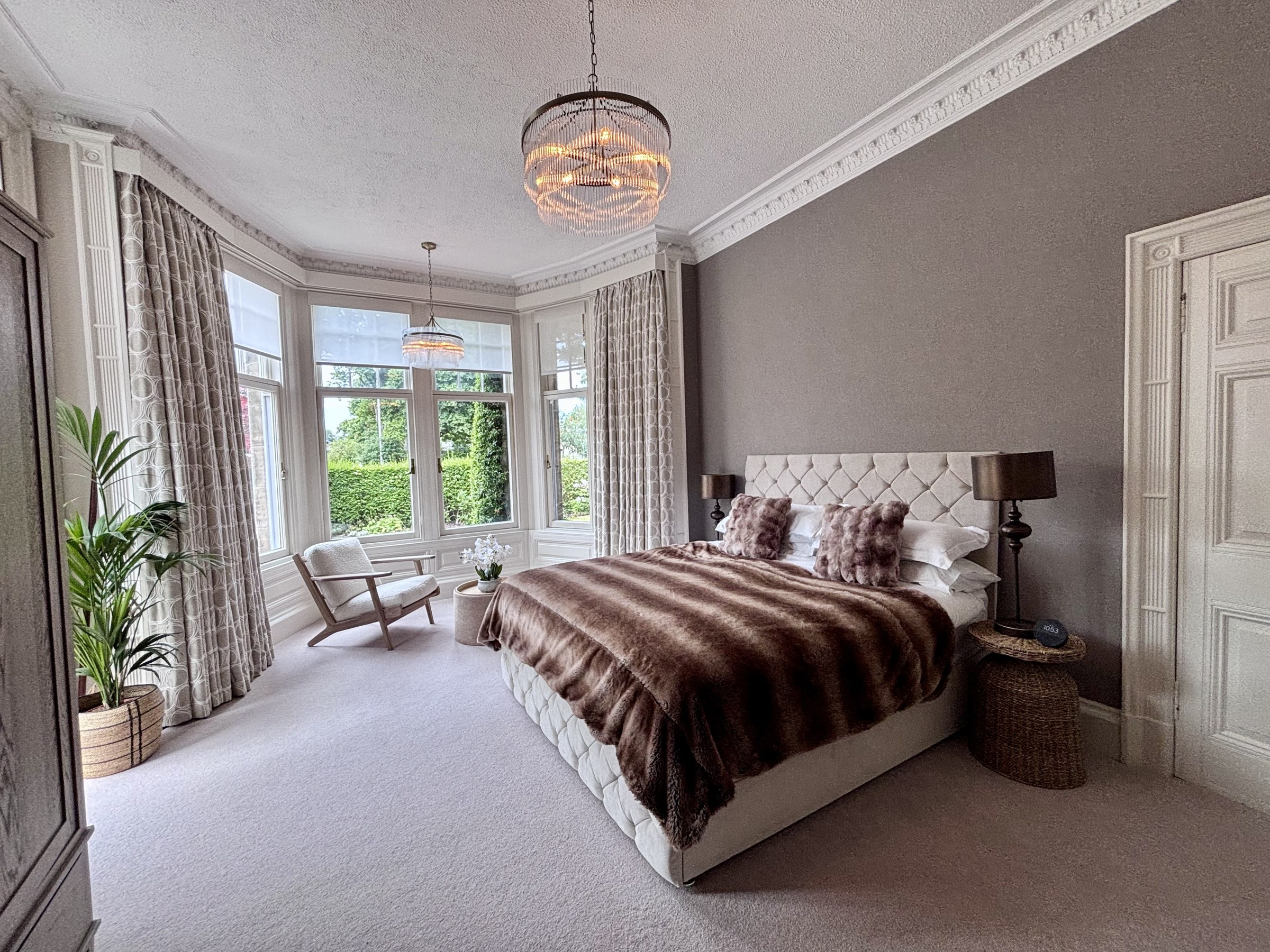 Bedroom with a bay window, double bed and patterned throw